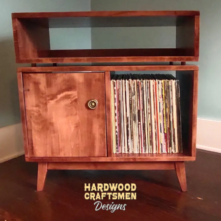 Low-profile solid maple record console with a turntable shelf, media bay, 1 lower door, 2 storage bins, and tapered mcm legs.