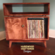 Low-profile solid maple record console with a turntable shelf, media bay, 1 lower door, 2 storage bins, and tapered mcm legs.