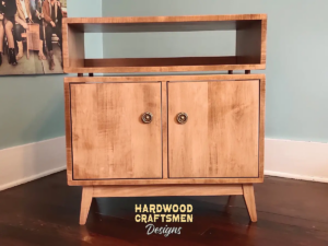 Vinyl cabinet with solid wood doors, upper turntable shelf, media equipment shelf, two divided storage compartments, two hardwood doors, and tapered mid-century legs.