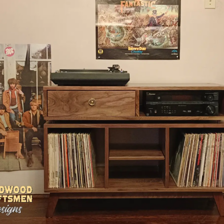 Record storage cabinet in solid walnut with a dovetail drawer and 3 vinyl storage bin compartments, available from 42 to 72 inches. This Media console features an upper TV shelf above three divided compartments, all on tapered mid-century legs.