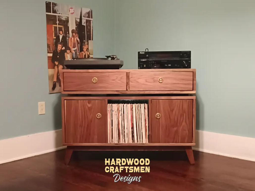 Solid walnut media console, available from 42 to 72 inches, featuring an upper TV shelf. Below are two drawers above three divided storage compartments, with two outer hardwood doors covering the side compartments, all on tapered mid-century legs.