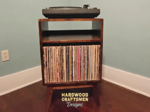 Small, narrow solid cherry dark-stain media console featuring an upper turntable shelf. The lower section includes a media cabinet with a storage compartment, all supported by tapered mid-century legs.