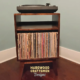 Small, narrow solid cherry dark-stain media console featuring an upper turntable shelf. The lower section includes a media cabinet with a storage compartment, all supported by tapered mid-century legs.