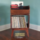 1x2 solid cherry record stand with upper vinyl record flip bin, one hardwood vinyl storage compartment, and tapered mid-century legs with crossbars.