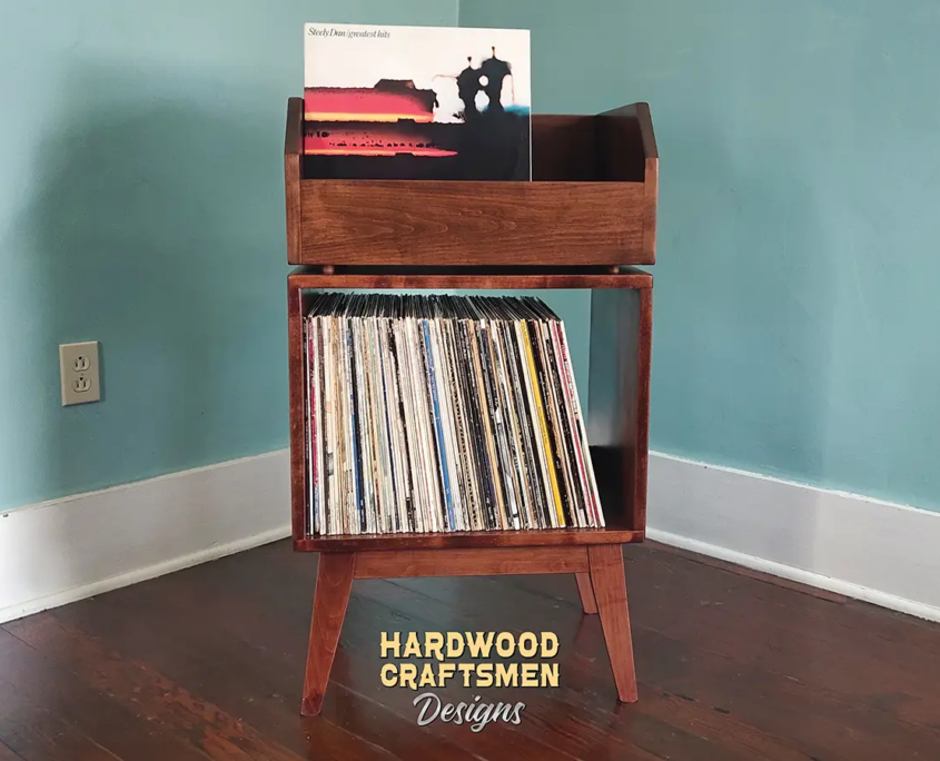 1x2 solid cherry record stand with upper vinyl record flip bin, one hardwood vinyl storage compartment, and tapered mid-century legs with crossbars.