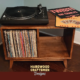 Solid maple record storage cabinet with 2 vinyl bins, media console with top turntable shelf, two open divided lower compartments, and tapered mid-century legs.