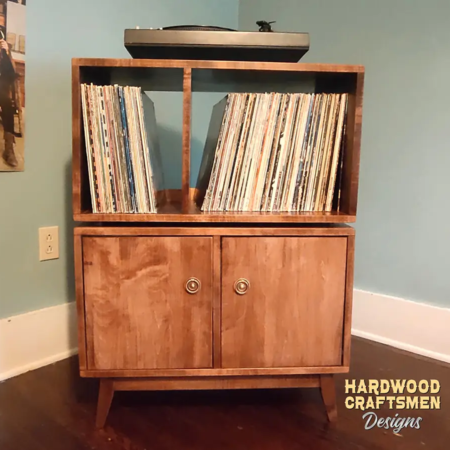 Large solid maple record cabinet, available from 28 to 48 inches wide, featuring an upper turntable shelf. Below are four storage compartments with two bottom doors, all on tapered mid-century legs.