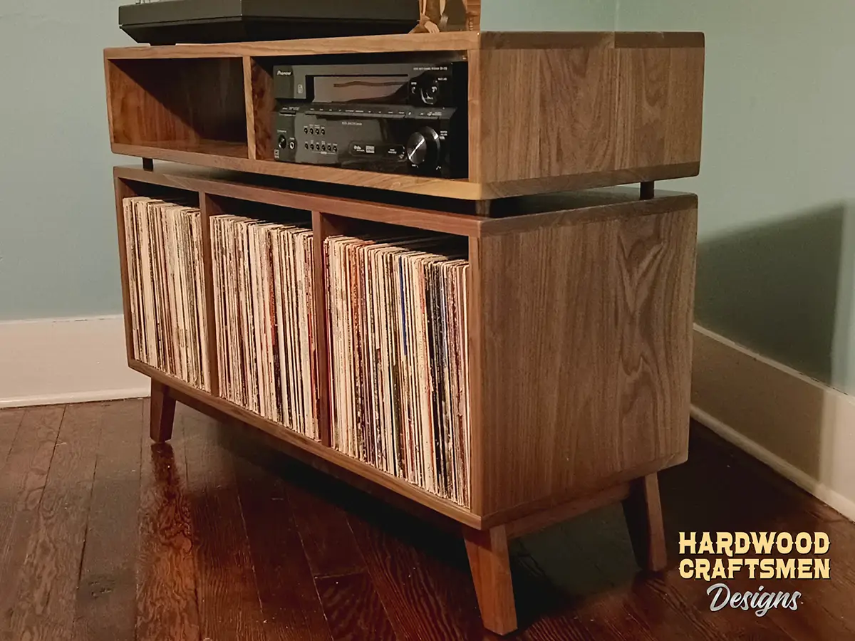 Solid walnut stereo cabinet with 2 media bays 3 x 1.5 layout with 3 vinyl bin compartments, available from 42 to 72 inches. This record player stand & audio console features an upper TV shelf above three divided compartments, all on tapered mid-century legs.