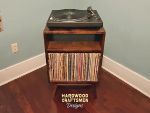 Small, narrow solid cherry dark-stain media console featuring an upper turntable shelf. The lower section includes an open media cabinet with a storage compartment below, all supported by tapered mid-century legs.