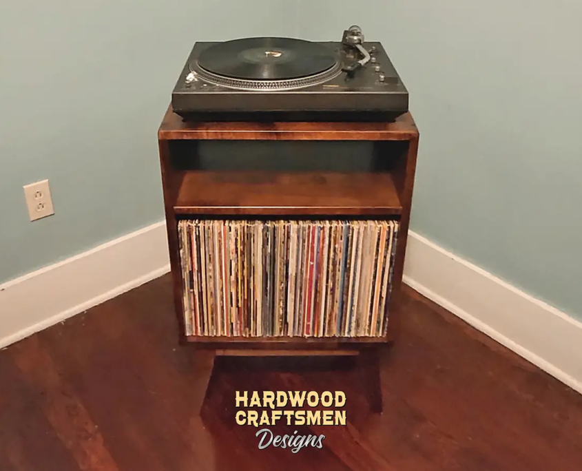 Small, narrow solid cherry dark-stain media console featuring an upper turntable shelf. The lower section includes an open media cabinet with a storage compartment below, all supported by tapered mid-century legs.