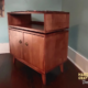 Vinyl cabinet with doors and upper turntable shelf, featuring two storage bins, two cabinet doors, and open shelves for a turntable and media equipment.