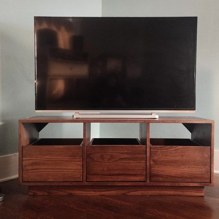 Dovetail 3 x 1 tv stand credenza features 3 pull out vinyl record storage drawers below a turntable & television shelf. This media console is available in solid walnut, ash, red oak, maple, cherry and oak, all on a 3 inch 100% hardwood plinth base.