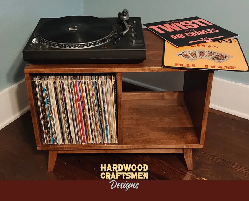 Low-profile solid maple record cabinet with top turntable shelf, two open divided lower compartments, and tapered mid-century legs.