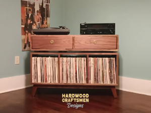 Large solid walnut media console, available from 42 to 72 inches, featuring an upper TV shelf. Below are two drawers above three divided storage compartments, all on tapered mid-century legs.
