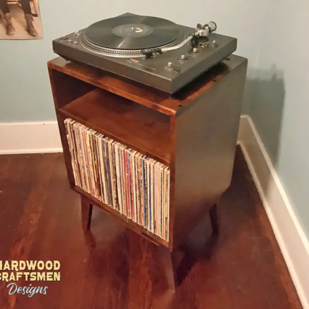 Small solid cherry wood media console with an upper turntable shelf, a media compartment below and a lower vinyl storage compartment, on tapered mid-century legs.