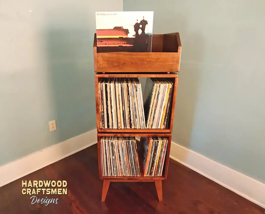 Narrow solid maple record stand with modular upper vinyl flip bin, two stacked storage compartments, and tapered mid-century legs.