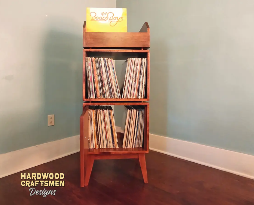 Narrow solid maple record stand with upper vinyl flip bin, two divided storage compartments, one lower hardwood door, and tapered mid-century legs.