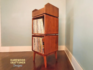 Tall solid cherry record cabinet with upper vinyl record flip bin, two stacked storage compartments, and tapered mid-century legs.