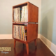 Record player cabinet vinyl storage with 2 bins built with solid maple wood, featuring a turntable shelf, two stacked storage compartments, and tapered mid-century legs.