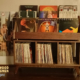 Large solid walnut record cabinet with 9 upper vinyl flip bins, six divided storage compartments, and tapered mid-century legs with crossbars.