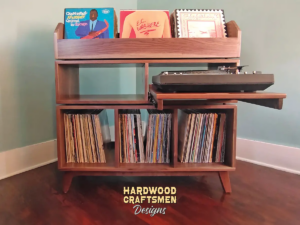 Tall, large solid walnut record cabinet featuring three upper vinyl flip bins. The lower section includes a protruding custom turntable shelf with an adjacent media shelf, above three divided storage compartments, all supported by tapered mid-century legs.