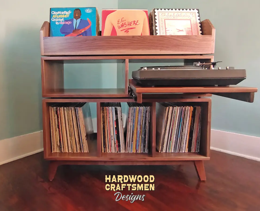 Tall, large solid walnut record cabinet featuring three upper vinyl flip bins. The lower section includes a protruding custom turntable shelf with an adjacent media shelf, above three divided storage compartments, all supported by tapered mid-century legs.