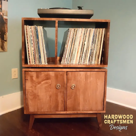 Large 2x2 solid wood record stand featuring a turntable shelf, four storage compartments with two doors on the lower level, and tapered mid-century legs.