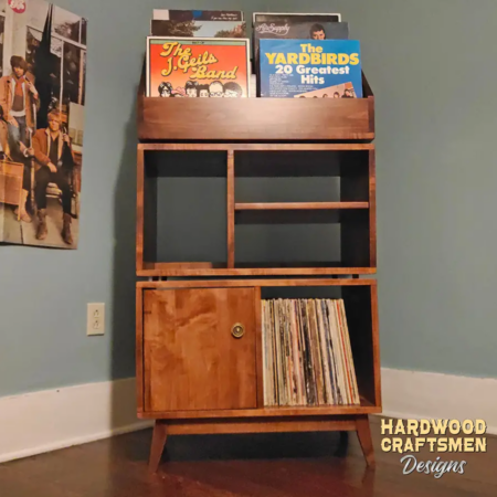 Tall solid maple record stand with six upper vinyl flip bins, four divided storage compartments, turntable and media shelves, hardwood door, and tapered mid-century legs.