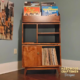 Tall solid maple record stand with six upper vinyl flip bins, four divided storage compartments, turntable and media shelves, hardwood door, and tapered mid-century legs.