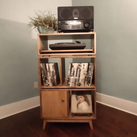 Large 2x3 solid wood record stand featuring a speaker shelf and a turntable pull-out shelf below, four storage compartments with a door on the bottom left, and tapered mid-century legs.
