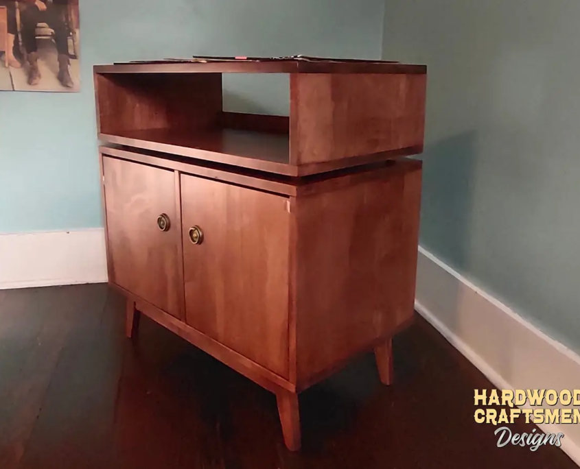 Large, narrow solid cherry medium-stain media console featuring an upper turntable shelf. The lower section includes a media cabinet with two side-by-side storage compartments enclosed by two doors, all supported by tapered mid-century legs.