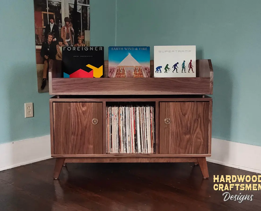 Large solid walnut record cabinet, 42 inches wide, featuring three vinyl flip bins above three storage compartments, with two outer doors covering the side compartments, all on tapered mid-century legs.