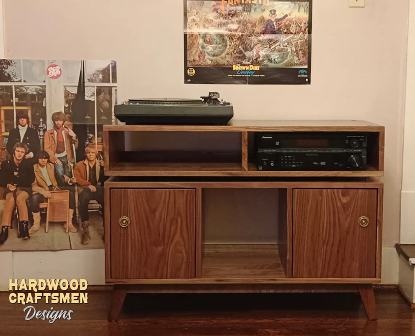 Large solid walnut media console, available from 42 to 72 inches, featuring an upper TV shelf. Below are two media compartments above three divided storage compartments, with two outer hardwood doors covering the side compartments, all on tapered mid-century legs.
