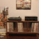 Solid walnut credenza 3 x 1 with vinyl record storage, available from 42 to 72 inches, featuring an upper TV shelf, two media shelves, and three divided storage compartments, all supported by tapered mid-century legs.