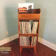 Tall solid maple record stand with modular upper vinyl record flip bin, two stacked storage compartments, and tapered mid-century legs.
