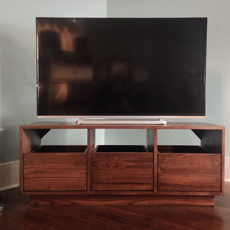 Dovetail 3 x 1 TV stand & entertainment center features 3 pull out vinyl storage drawers below a & television shelf. This record cabinet is available in solid walnut, ash, red oak, maple, cherry and oak, all on a 3 inch 100% hardwood plinth base.