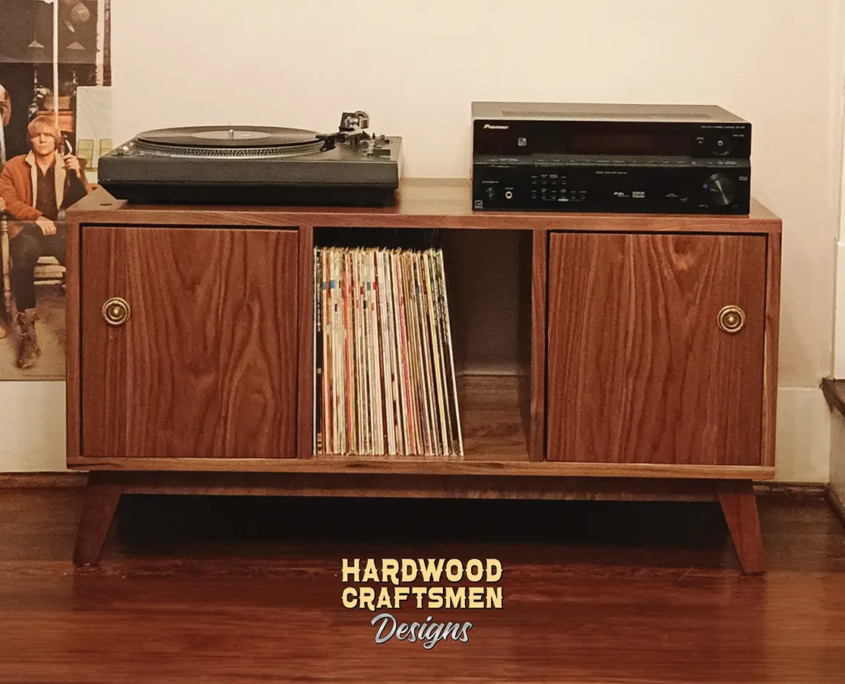 Solid walnut media console with doors, available from 42 to 72 inches, featuring an upper TV shelf above three divided storage compartments, with two outer hardwood doors covering the side compartments, all on tapered mid-century legs.