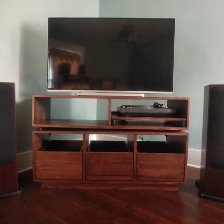 Dovetail 3 x 2 media & tv console features a custom turntable shelf and 3 pull out vinyl record storage drawers below an audio equipment shelf. This television stand is available in solid walnut, ash, red oak, maple, cherry and oak, all on a 3 inch 100% hardwood plinth base.